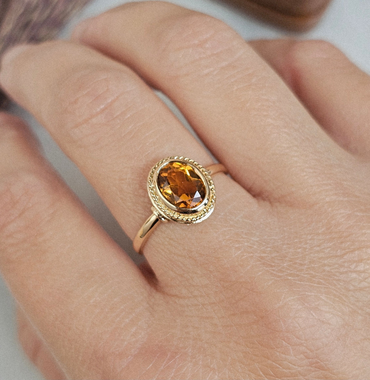 Bague ancienne en or 18 carats sertie d'une citrine ovale entourée d'un motif tressé, travail français, vue portée