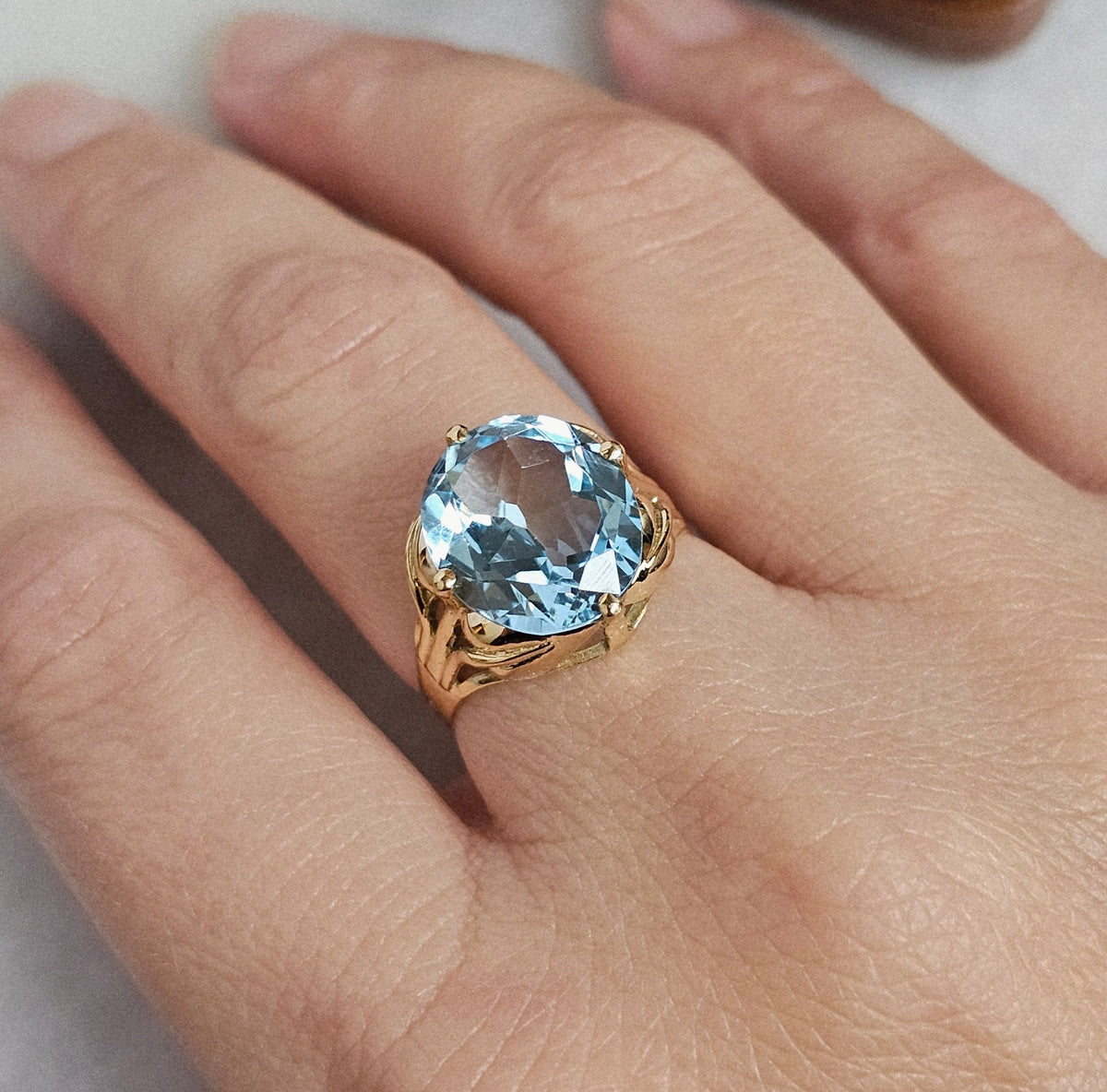 Bague cocktail vintage en or jaune sertie d'une importante topaze ovale dans un décor végétal, vue portée