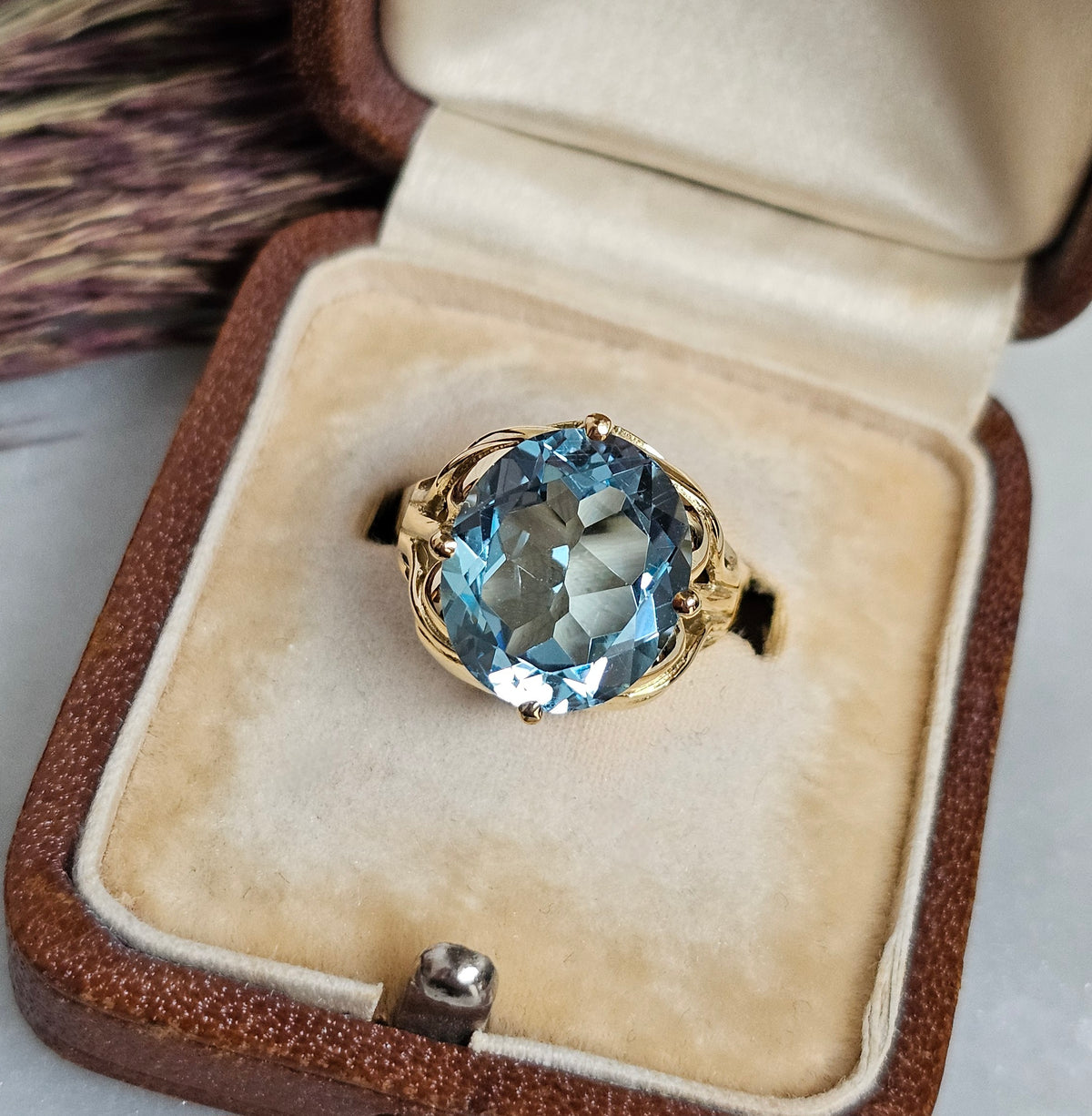 Bague cocktail vintage en or jaune sertie d'une importante topaze ovale dans un décor végétal, gros plan dessus