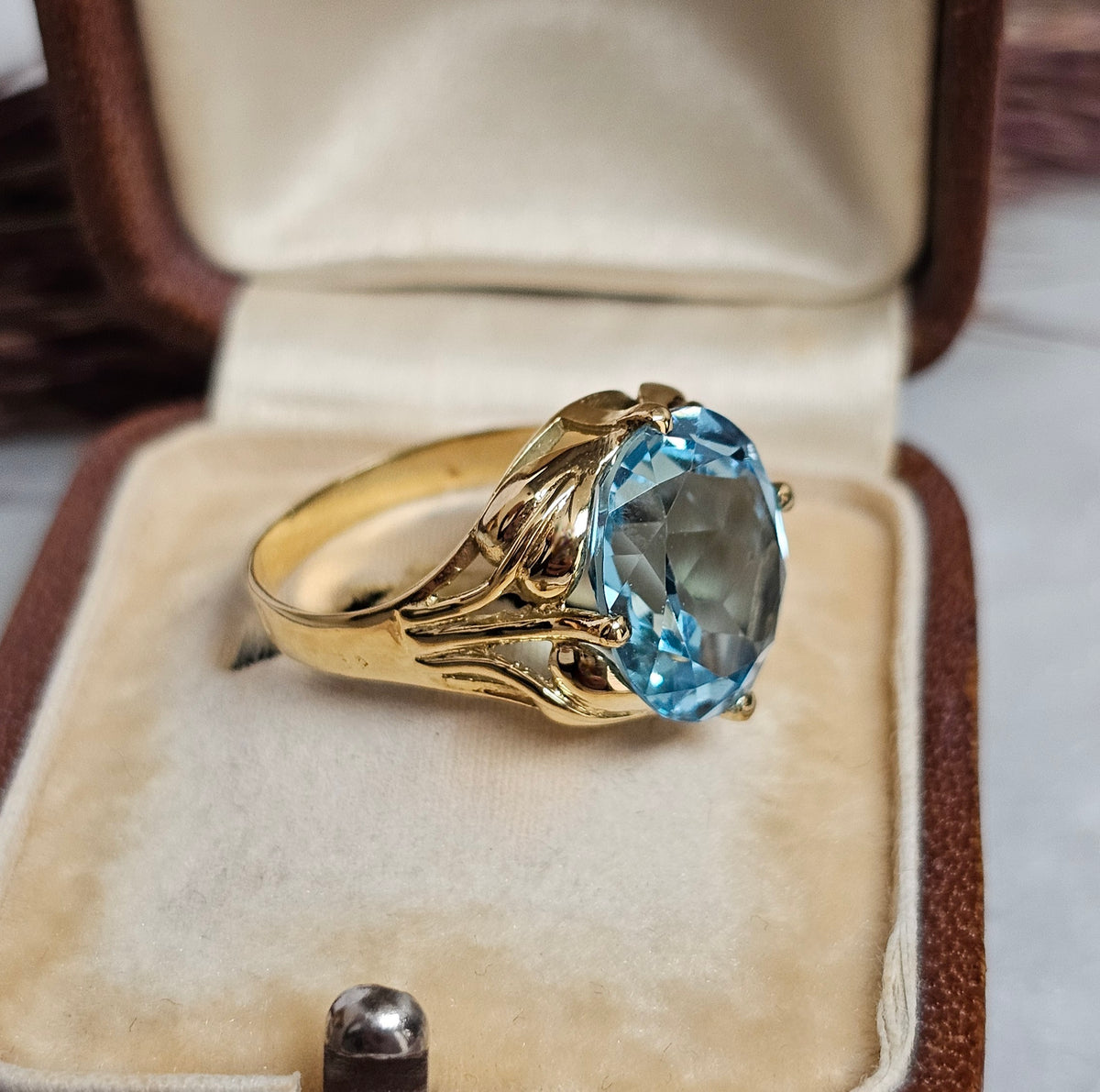 Bague cocktail vintage en or jaune sertie d'une importante topaze ovale dans un décor végétal, vue de profil