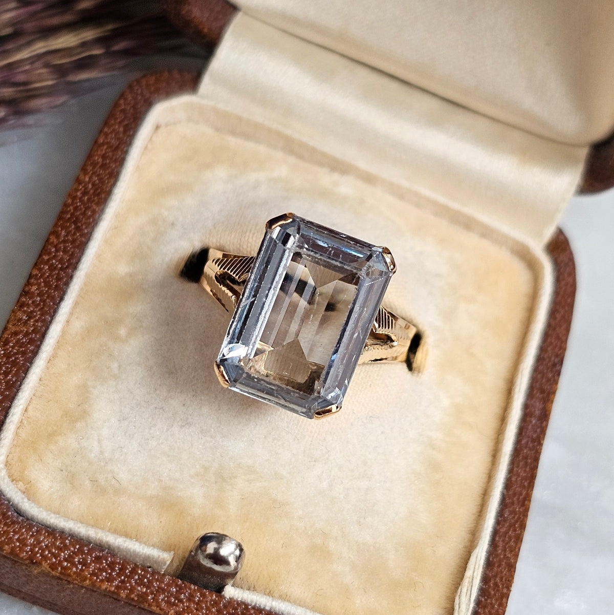 Bague cocktail vintage vers 1950 en or 18 carats et pierre bleue rectangulaire de type spinelle. La monture présente un dessin ajouré et strié, vue du dessus