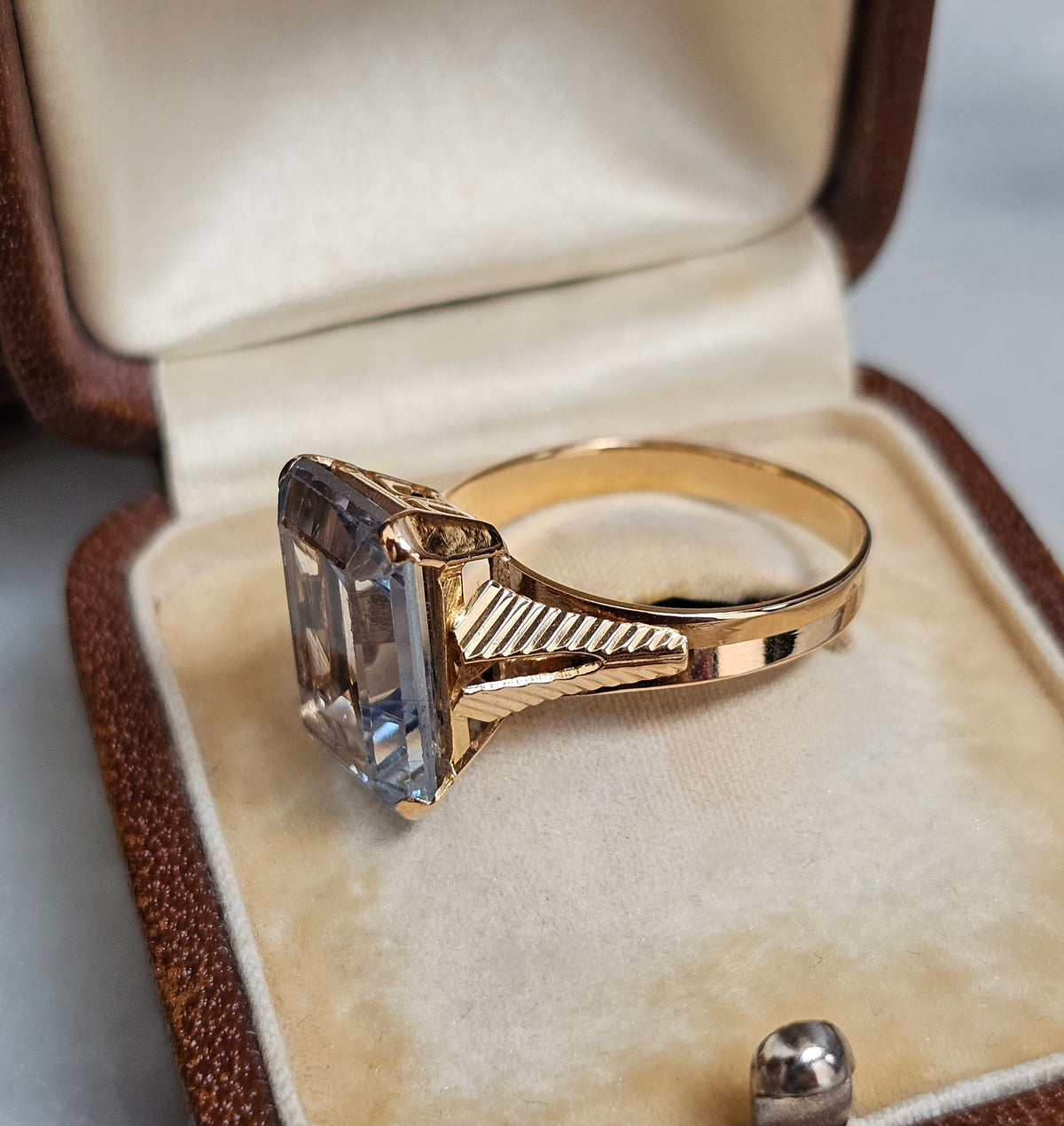 Bague cocktail vintage vers 1950 en or 18 carats et pierre bleue rectangulaire de type spinelle. La monture présente un dessin ajouré et strié, vue de profil