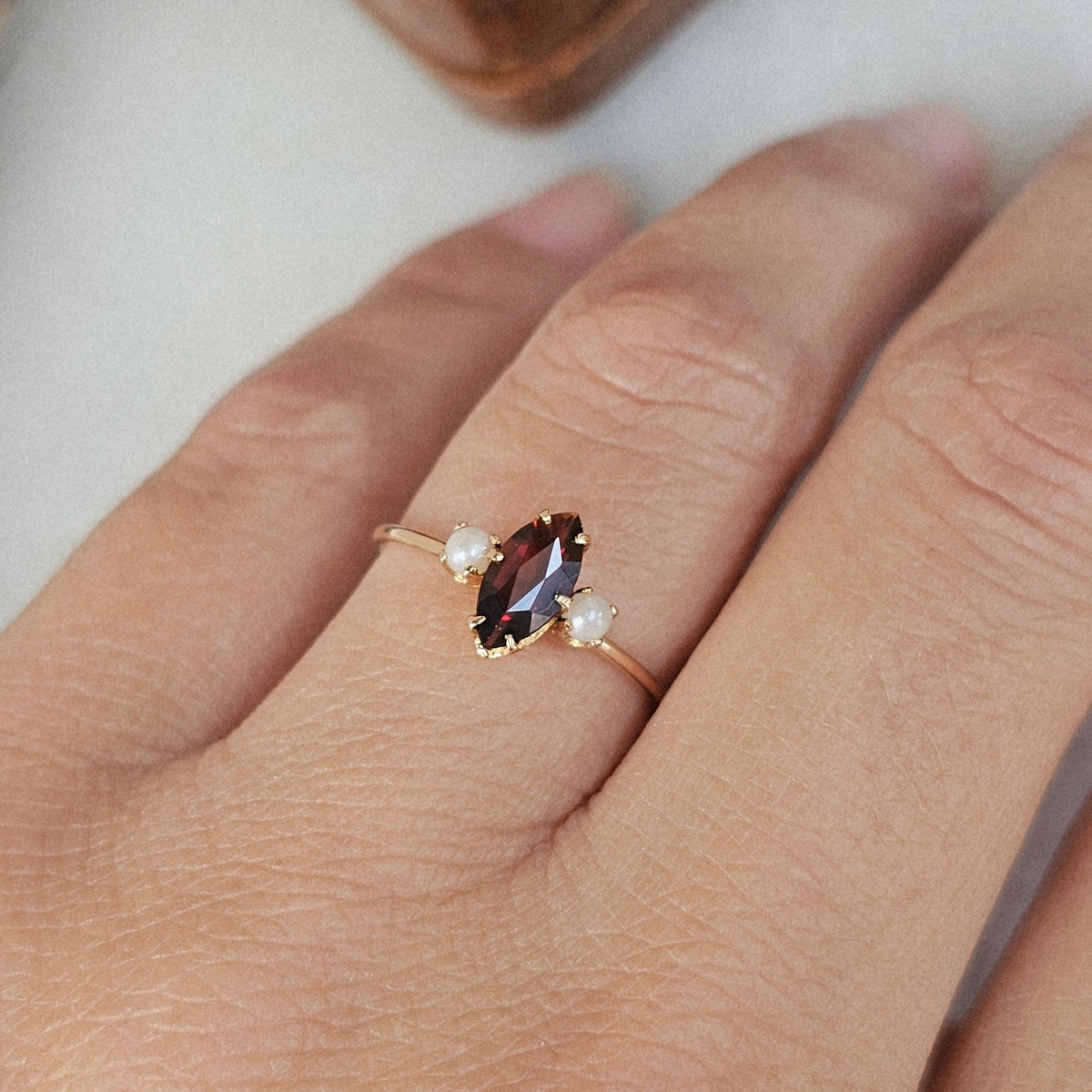 Bague fine ancienne en or rose, de style trilogie, sertie d'un grenat forme marquise et de deux perles, vue portée