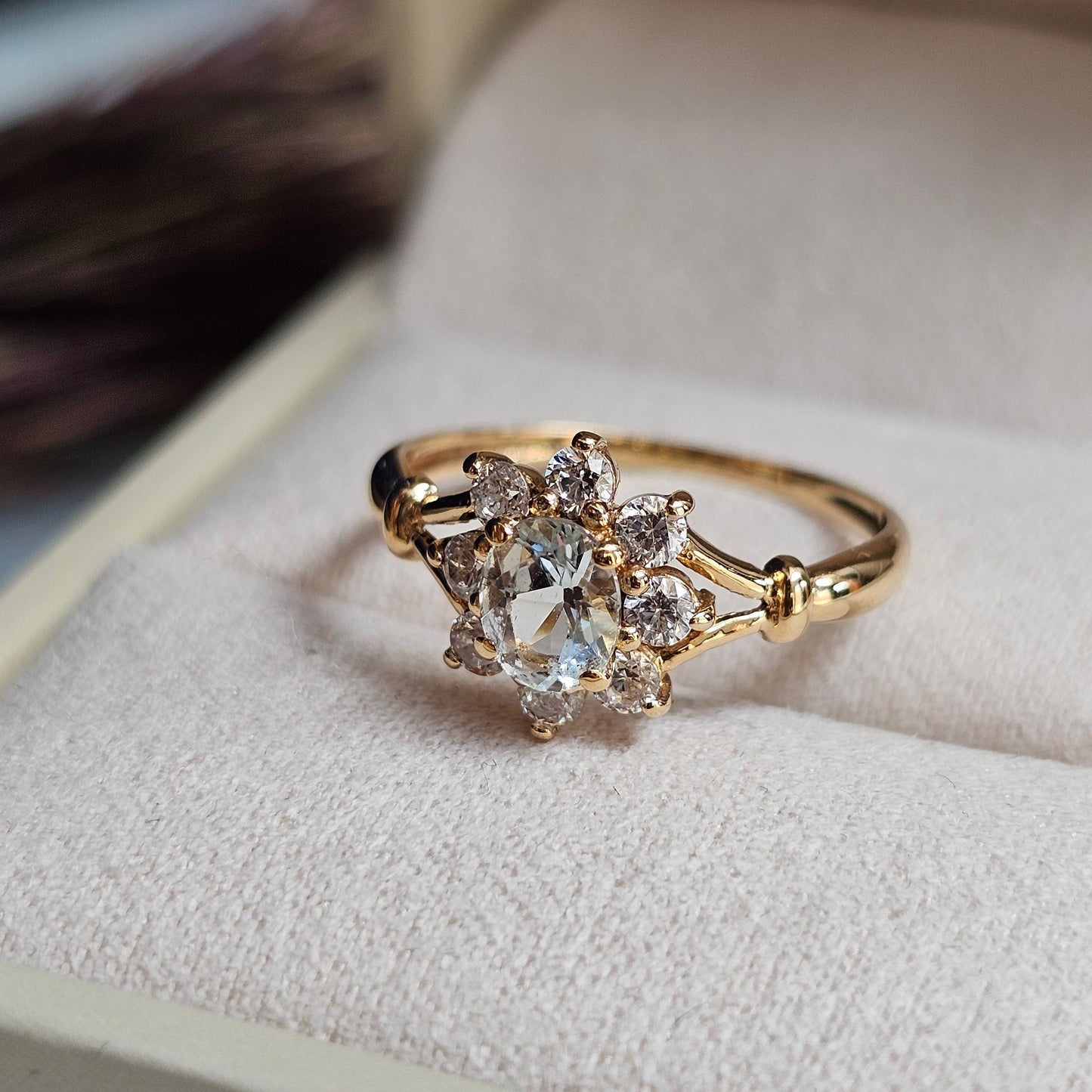 Bague marguerite vintage en or jaune 18 carats sertie d'une aigue-marine bleu pâle dans un entourage de pierres blanches imitant le diamant. 