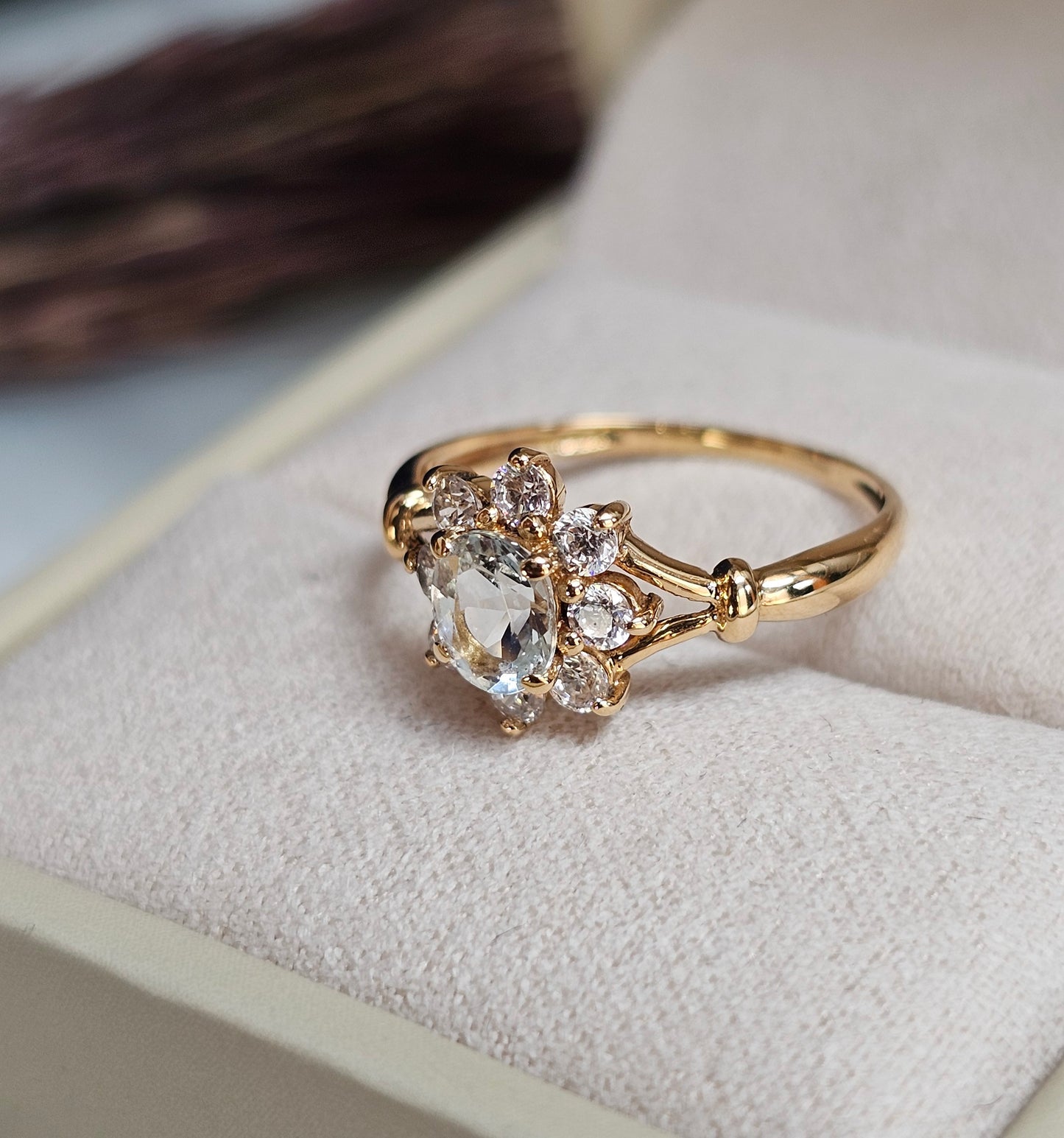 Bague marguerite vintage en or jaune 18 carats sertie d'une aigue-marine bleu pâle dans un entourage de pierres blanches imitant le diamant, vue sur le côté.