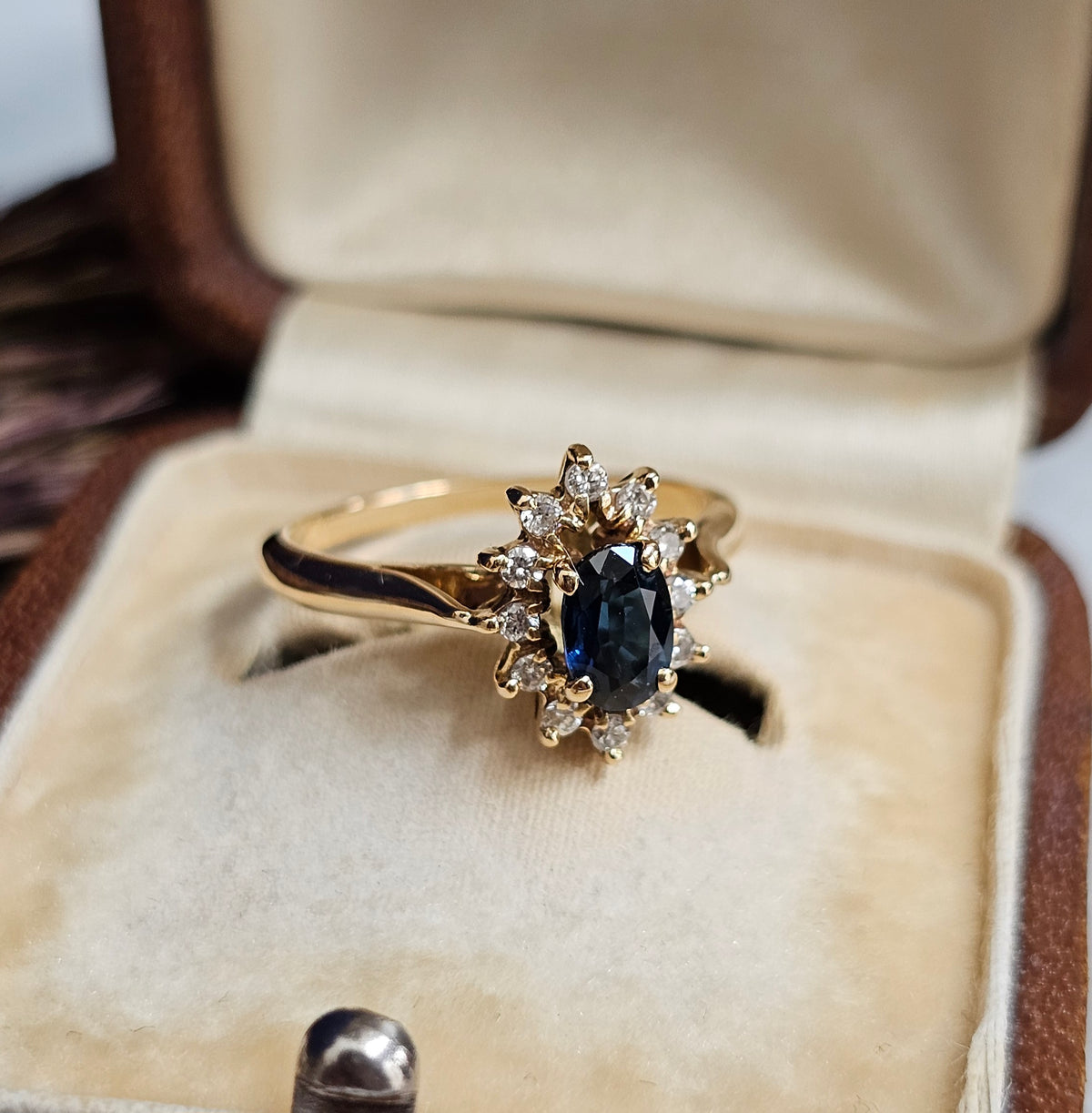 Bague de fiançailles type marguerite, avec saphir et diamants, sur une monture en or jaune 18 carats, vue de profil