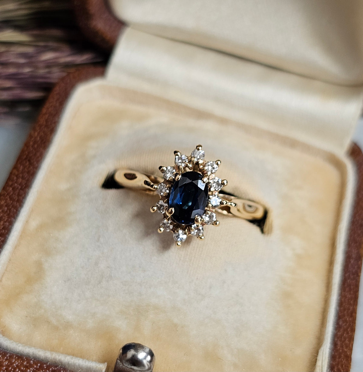 Bague de fiançailles type marguerite, avec saphir et diamants, sur une monture en or jaune 18 carats, gros plan