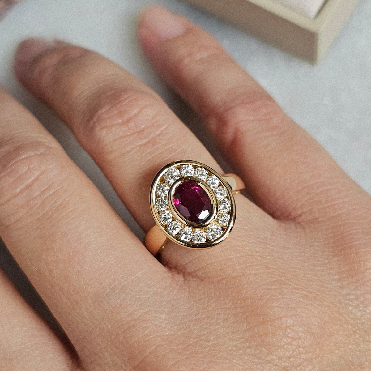 Bague vintage vers 1990 de forme ovale, aux lignes Art Déco, en or jaune, sertie d'un rubis et de diamants, vue portée