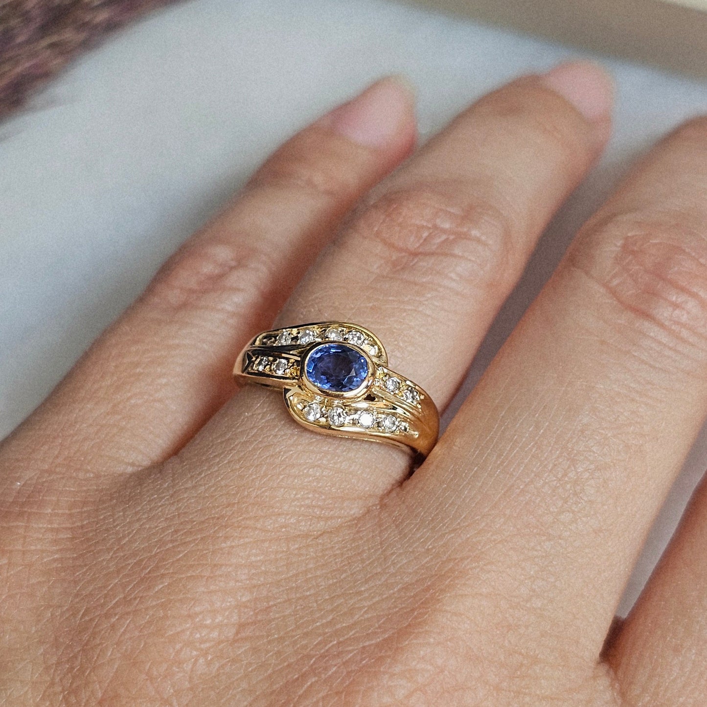 Bague vintage en or jaune 18 carats sertie d'un saphir ceylan bleu lavande et de diamants, vue portée.