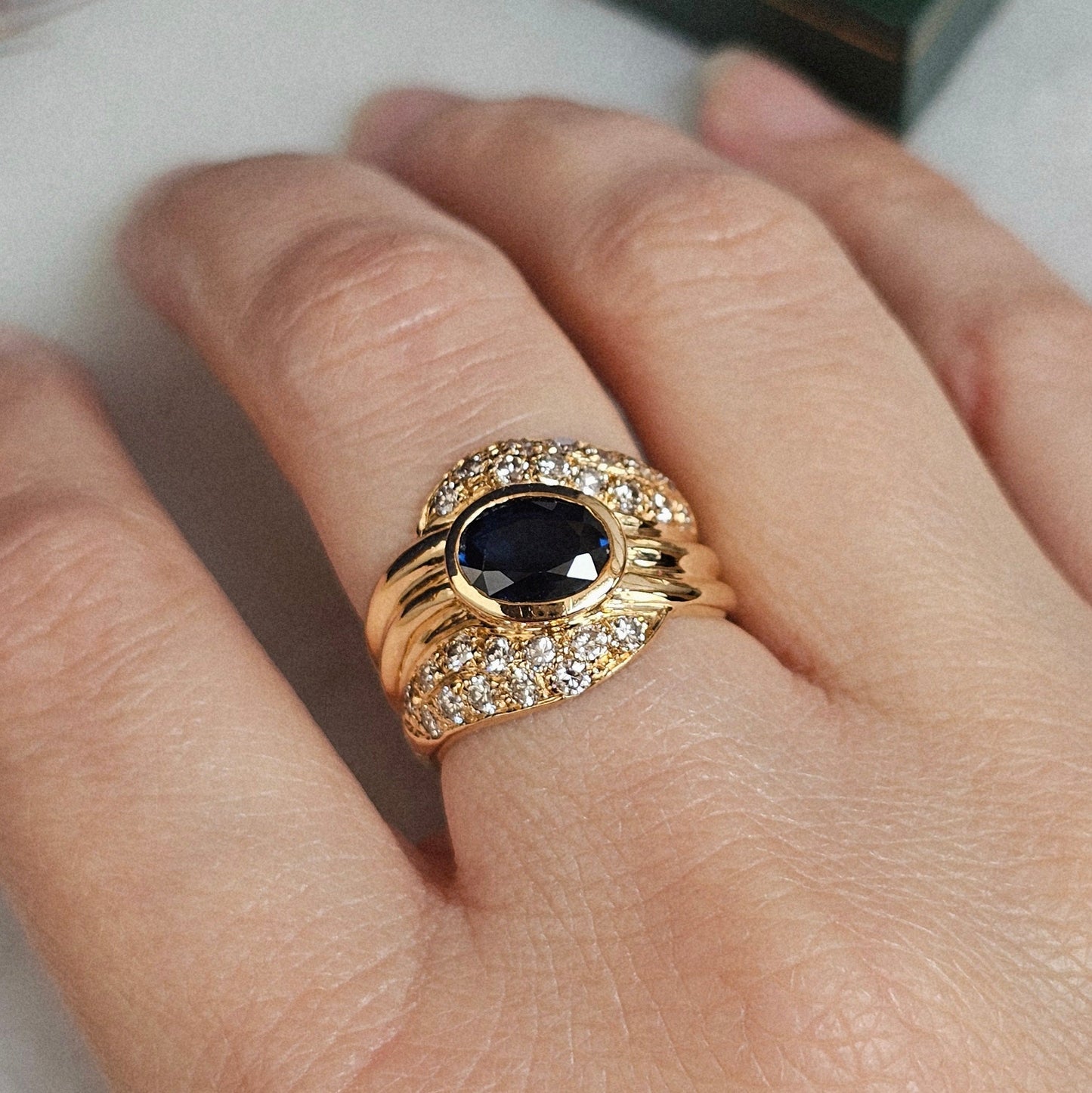 Bague vintage, type cocktail, vers 1980 en or jaune 18 carats, sertie d'un saphir et de diamants, portée.