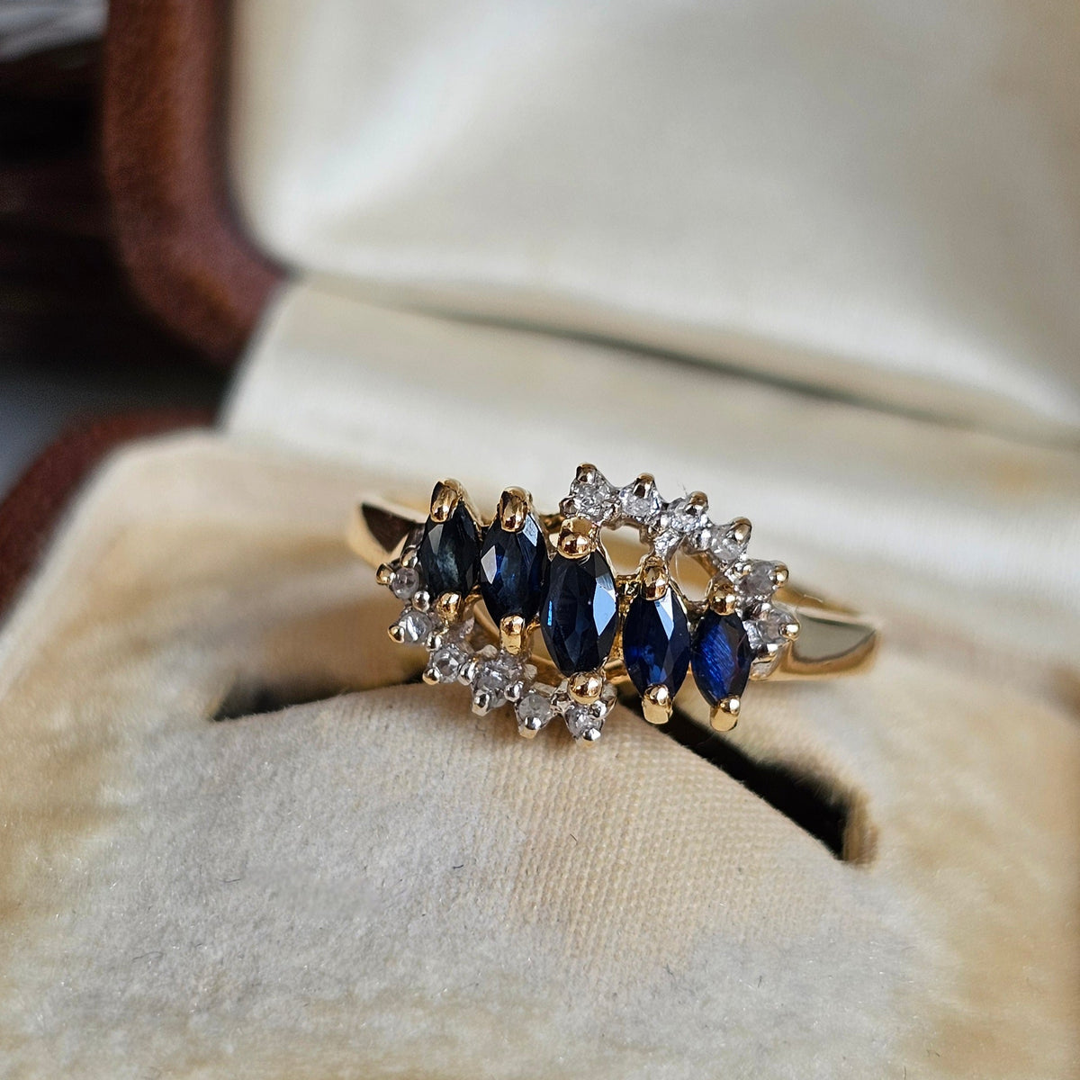 Bague vintage style rivière, sertie d'une ligne centrale de saphirs taille navette, encadré de deux lignes de diamants sur une monture en or jaune 18 carats, vers 1990, vue de face.