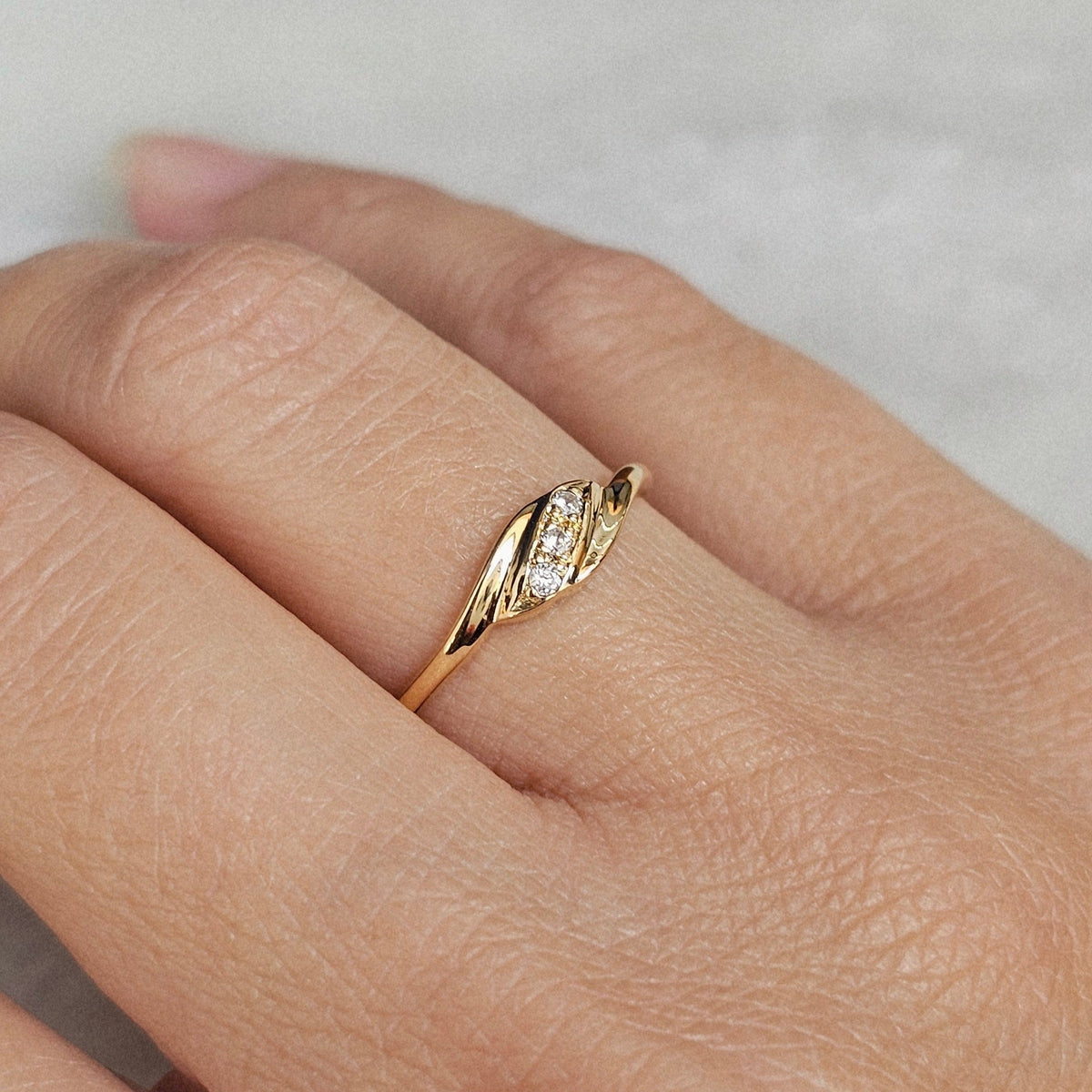 Bague vintage fine en or jaune, de style trilogie, sertie de trois pierres blanches, vue portée