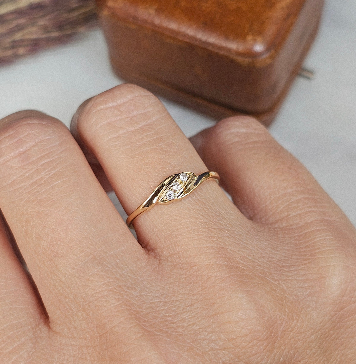 Bague vintage fine en or jaune, de style trilogie, sertie de trois pierres blanches, autre vue portée