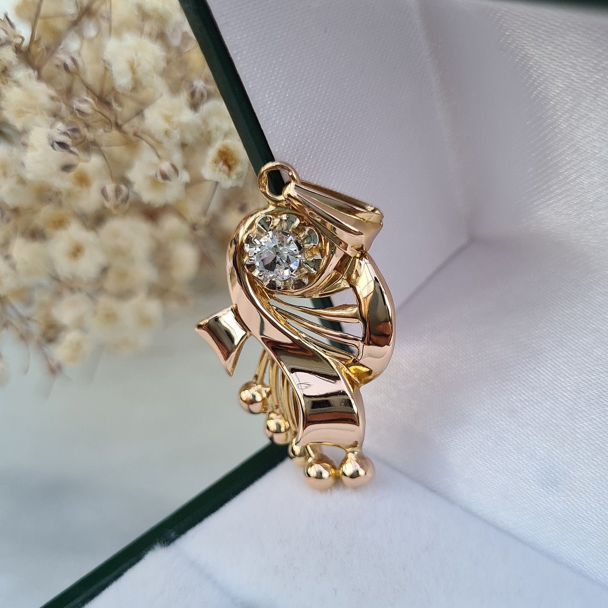 Pendentif vintage de forme entrelacée, rappelant l'univers musical, en or 18 carats et pierre blanche imitant le diamant, gros plan