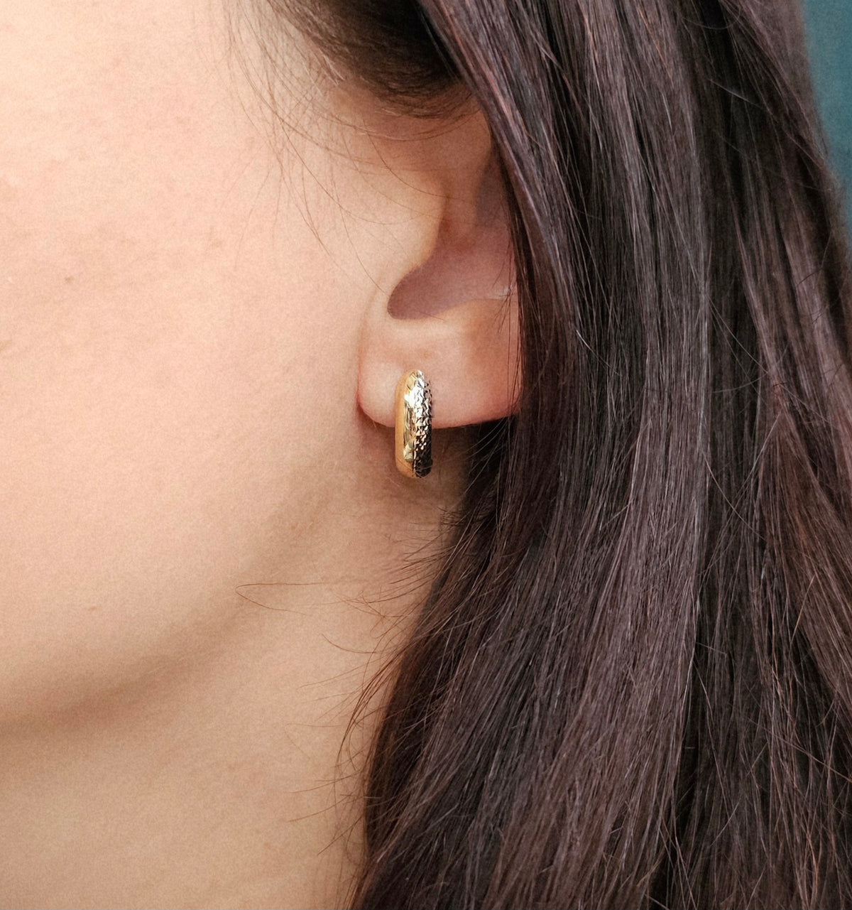 Boucles demi-créoles en or deux tons, blanc et jaune, avec une partie lisse en or jaune et l'autre en or blanc texturé, vue portée